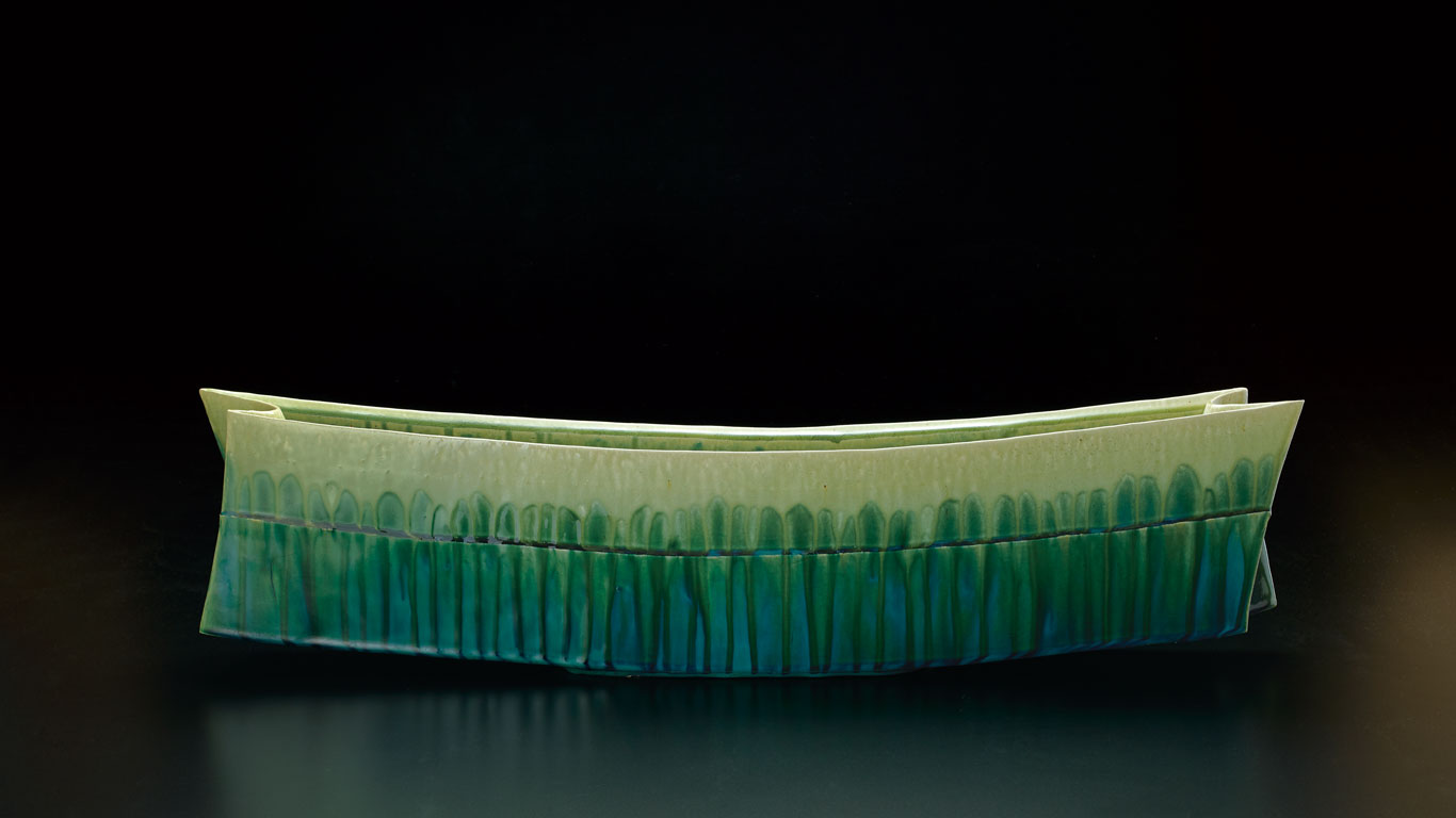 鈴木徹さんは「『萌生』シリーズの作品です。これまで薄緑色と濃緑色の二つの塗り分けによる表現が中心でしたが、最近は緑のなかに青色が出て多彩になるように釉薬を調合しています。草木が萌出る際の“瑞々しさと力強さ”を見とって貰えたら嬉しい限りです。」 と話した。  奥行12.5 幅66.0 高18.5 cm　©Tetsu Suzuki